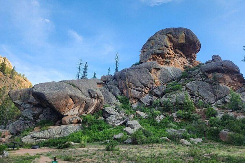 A large rock formation with a prominent overhang, surrounded by smaller rocks and sparse vegetation. 1