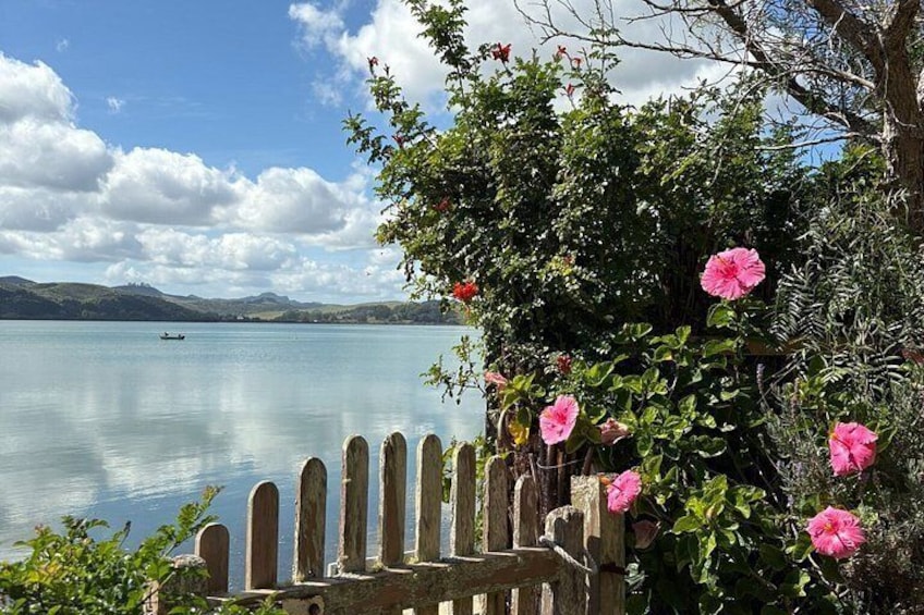 A calm lake with a wooden fence and pink flowers in the foreground. 3