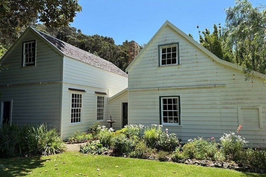 Two white wooden houses with gabled roofs, surrounded by a well-maintained garden with various plants and flowers. 1
