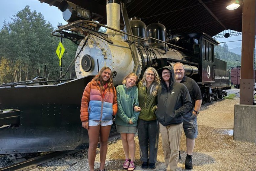 A group of people standing in front of a steam locomotive with the number 9. 4