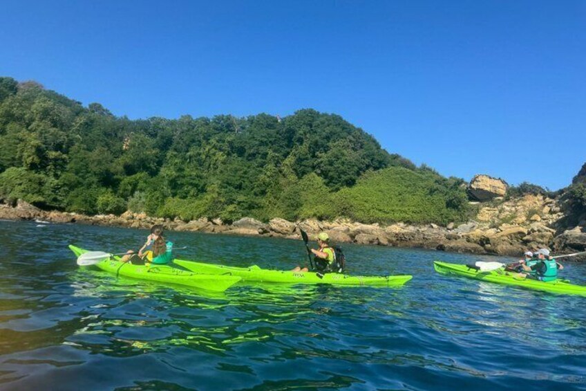 Three people kayaking on a calm river with a forested hillside in the background. 2