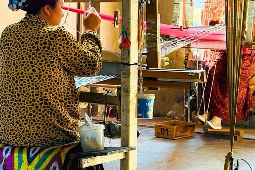A person working with a loom, surrounded by textile materials and tools. 3
