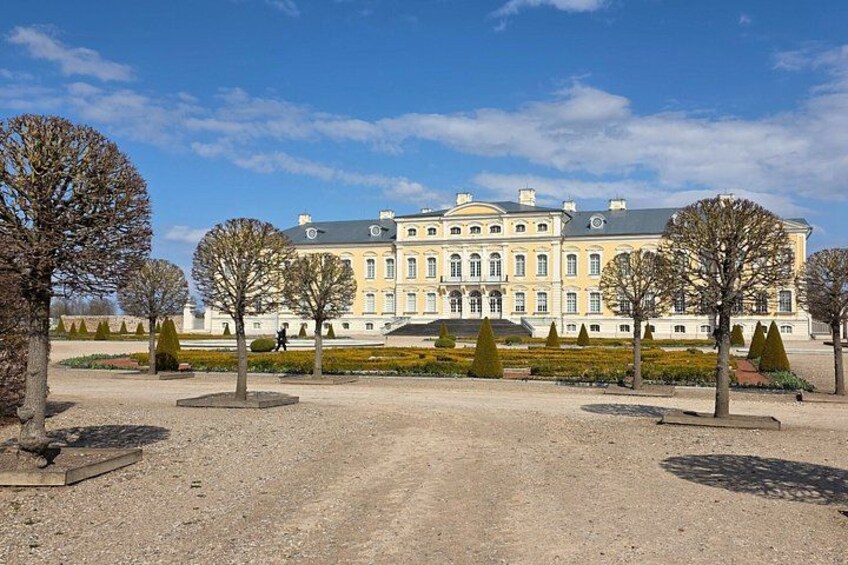 A large, classical building with symmetrical architecture, surrounded by a formal garden with neatly trimmed hedges and trees. 5