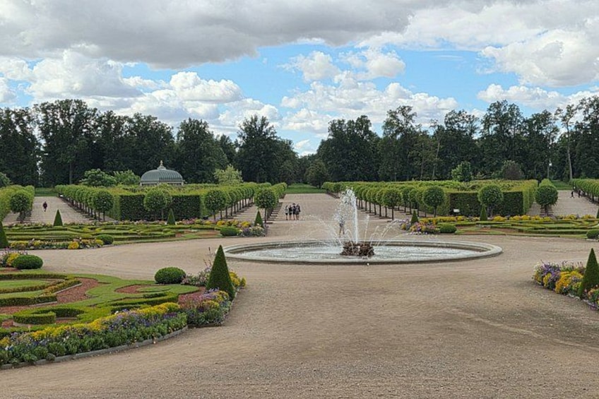 A formal garden with a central fountain, neatly trimmed hedges, and a dome structure. 5