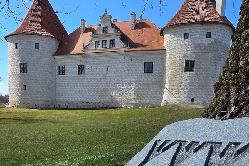 A castle with two round towers, a red roof, and a stone wall. 3