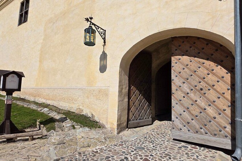 A stone-paved entrance with a wooden door and a lantern above it. 2