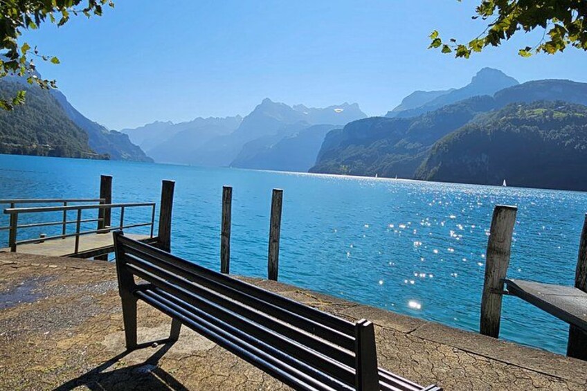 A bench by a lake with mountains in the background. 1