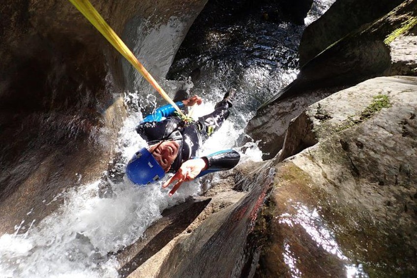 Two individuals rappelling down a rocky watercourse. 1