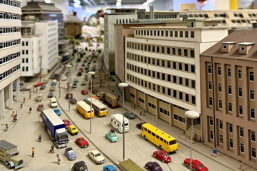 A detailed model cityscape with miniature buildings, streets, and vehicles. 3