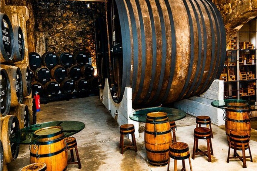 A cellar with wooden barrels, a large barrel, and a fire extinguisher. 3