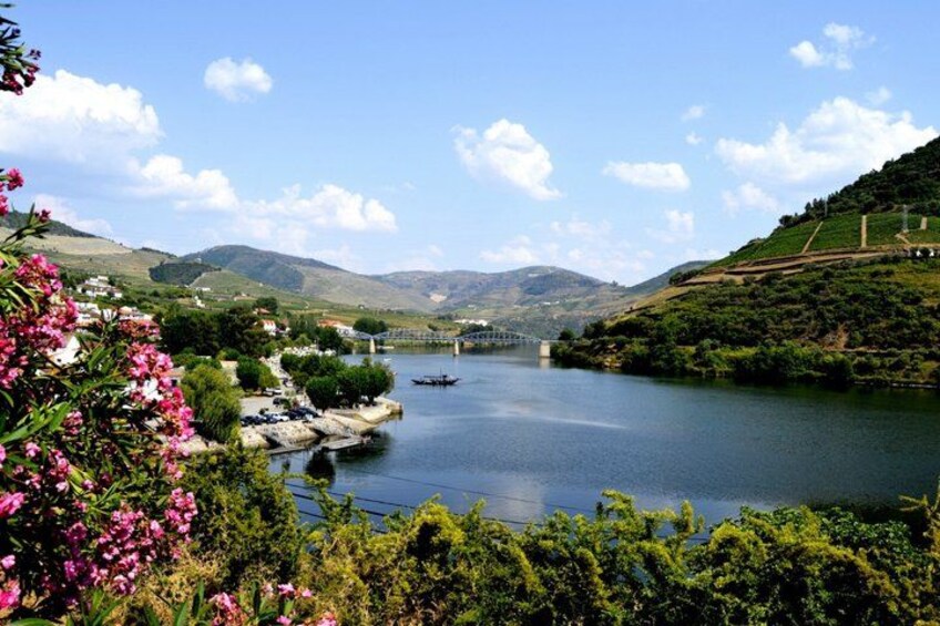 A calm lake with boats, a bridge, and hills in the background. 4