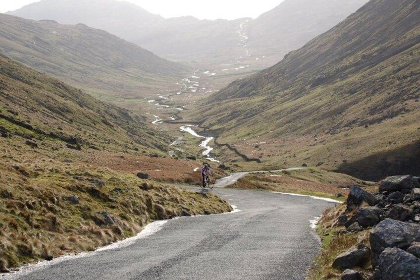 A cyclist on a narrow mountain road with a river in the valley. 5