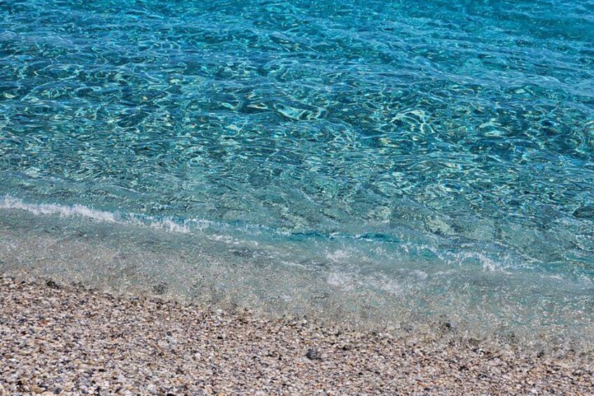 Clear blue water, a pebbly beach, and a sandy shore. 5