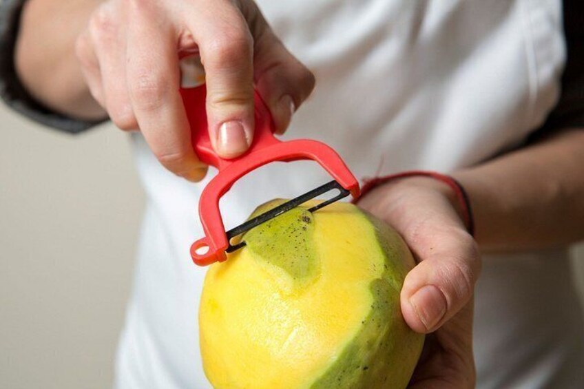 A person using a red and black fruit slicer to cut a yellow fruit. 5