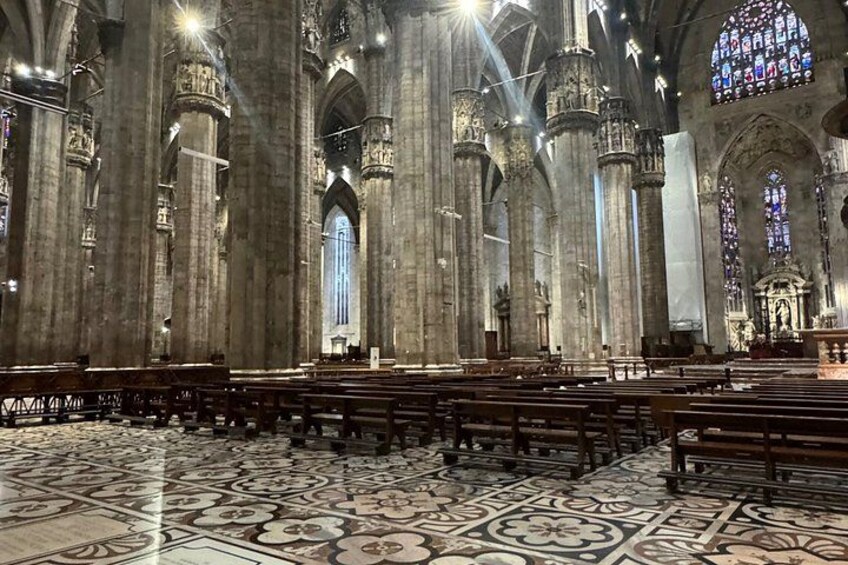 A cathedral interior with high ceilings, large stained glass windows, and ornate columns. 2