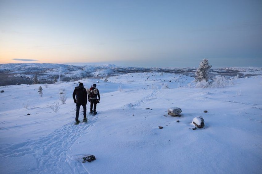 Two people hiking on a snow-covered trail with a view of a distant landscape. 5