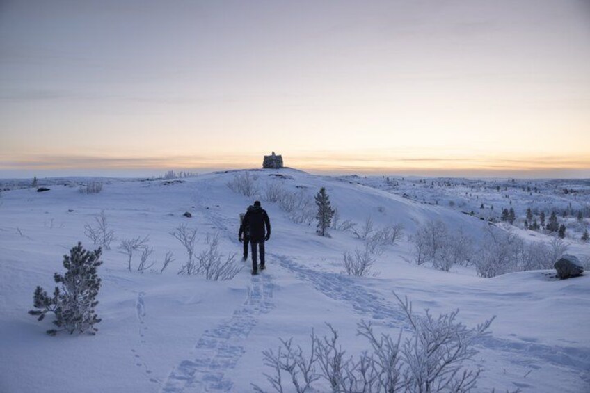 A person walking on a snowy path with a building in the distance. 3