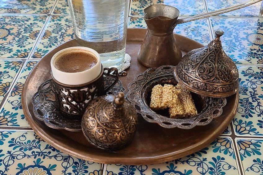 A tray with a cup of coffee, a teapot, a sugar bowl, and a water pitcher on a tiled table. 5