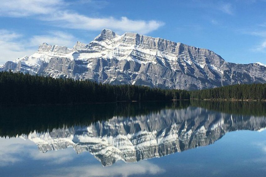 A mountain range with snow-capped peaks reflected in a calm lake. 3
