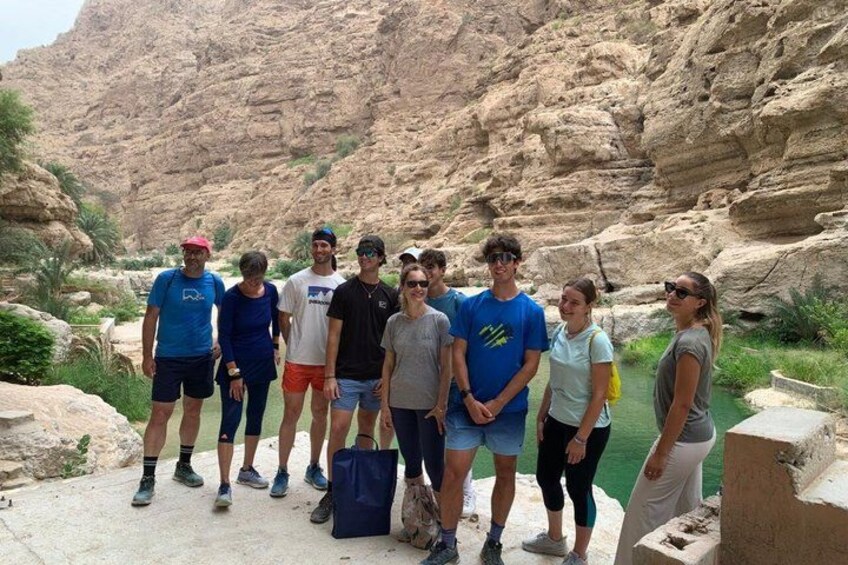 A group of people standing in a rocky outdoor setting with a canyon in the background. 4