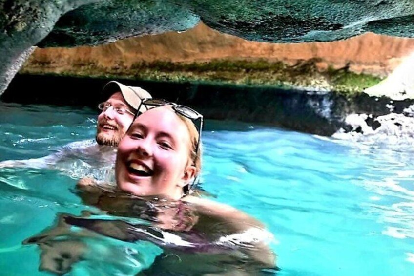 A person swimming in a clear blue pool with a rocky background. 1