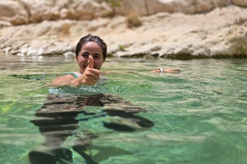 A person swimming in clear water with a rocky background. 2