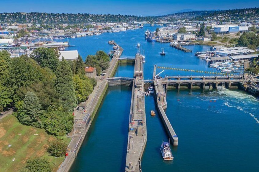 A lock system in a river with boats, a bridge, and surrounding buildings. 2