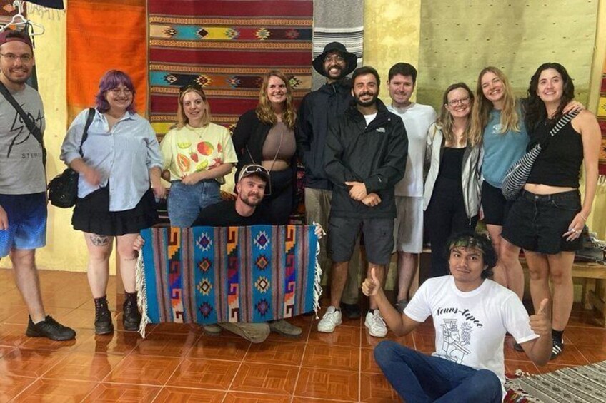 A group of people posing in an indoor setting with patterned rugs and a wooden floor. 3