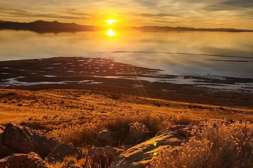 A sunset over a dry, rocky landscape with sparse vegetation. 3