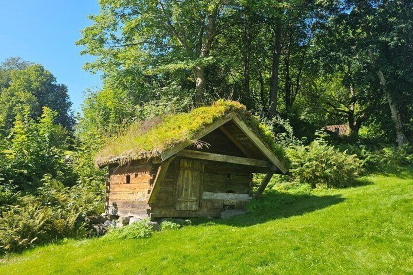 A wooden cabin with a thatched roof surrounded by lush greenery. 4