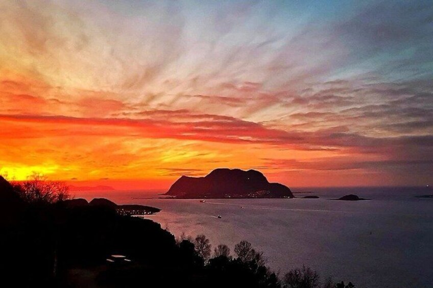 A sunset over a calm sea with distant landforms and a clear sky. 2