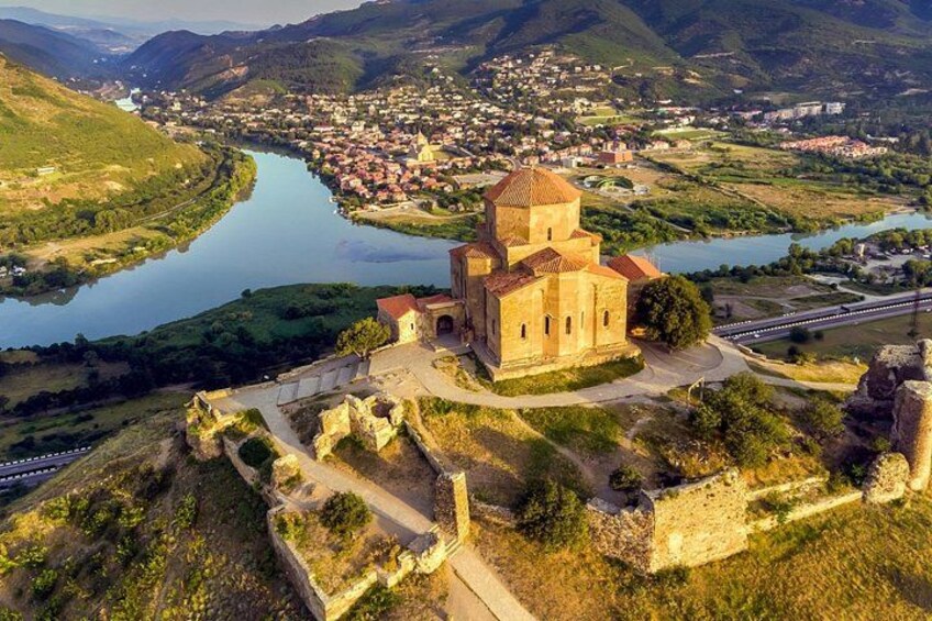 A historic church with a bell tower, surrounded by a river, a bridge, and a town in the background. 1
