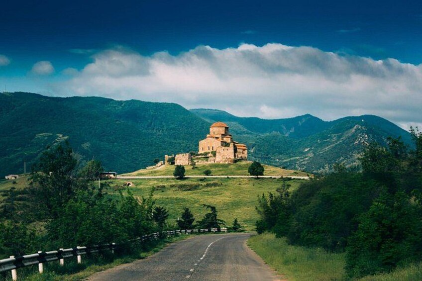 A historic building on a hilltop with a road leading to it. 2