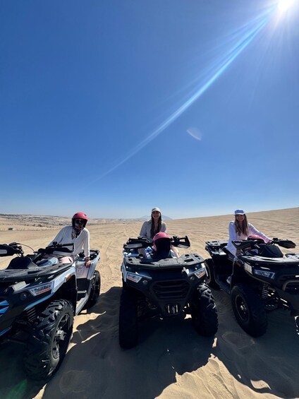 Three people on ATVs in a desert with a clear sky. 2