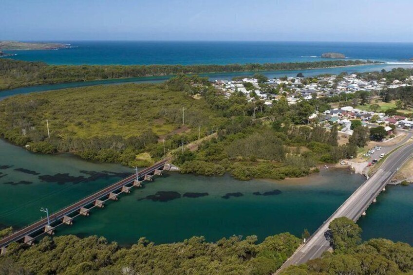 A bridge over a body of water, surrounded by greenery and a small settlement. 2