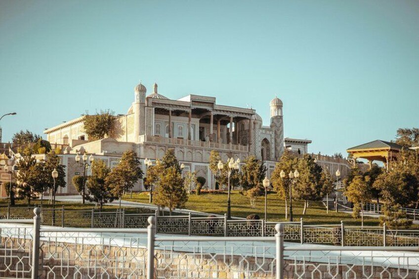 A large, historic building with domes and arches, surrounded by a fence and trees. 2