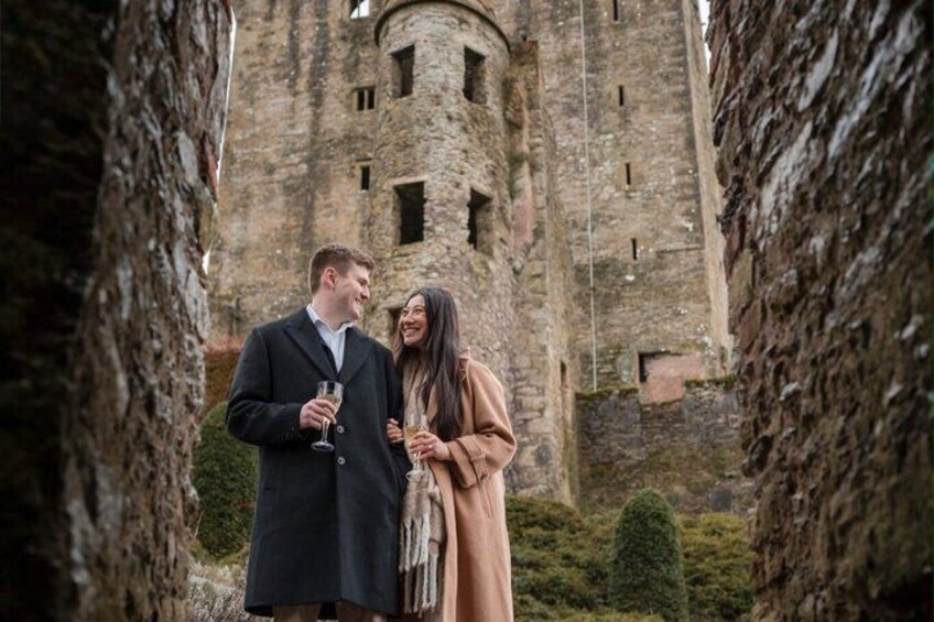 A couple standing in front of a historic stone tower. 1