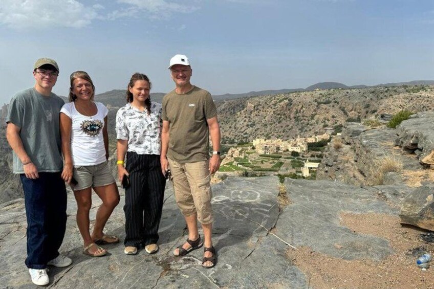 A group of people standing on a rocky outcrop with a village in the background. 2