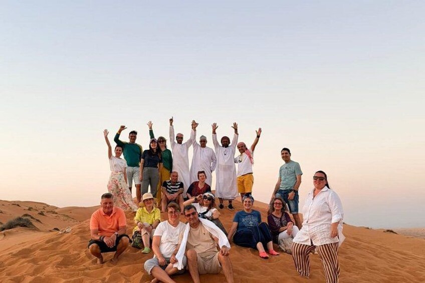 A group of people in a desert setting with sand dunes in the background. 4