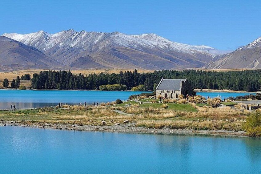 A lake, a building, and snow-capped mountains. 1