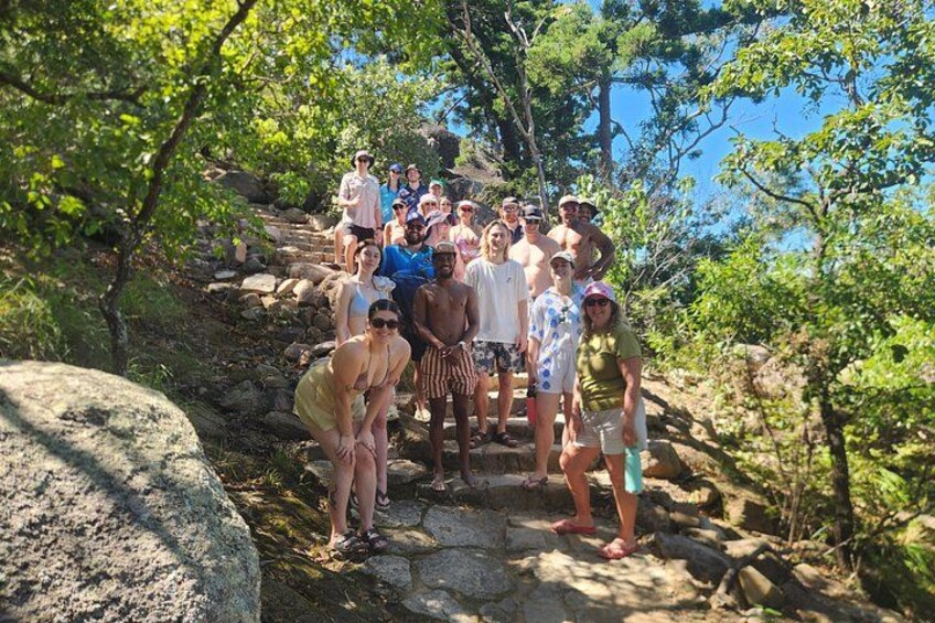 A group of people hiking on a rocky trail surrounded by trees. 2