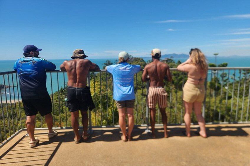 A group of people standing on a viewing platform overlooking a coastal landscape. 5