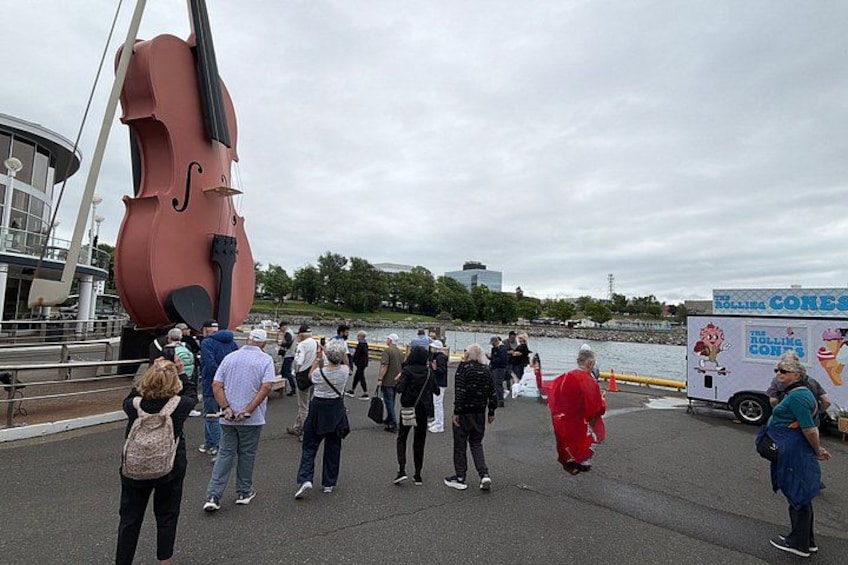 A large musical instrument sculpture, a crowd of people, and a food truck. 2