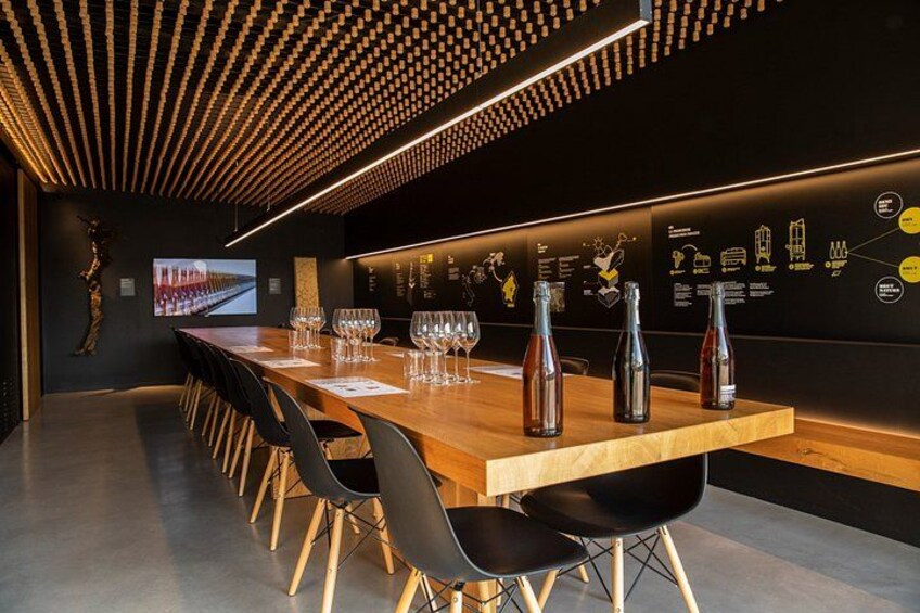 A modern bar with a wooden table, black chairs, and illuminated wall art. 4