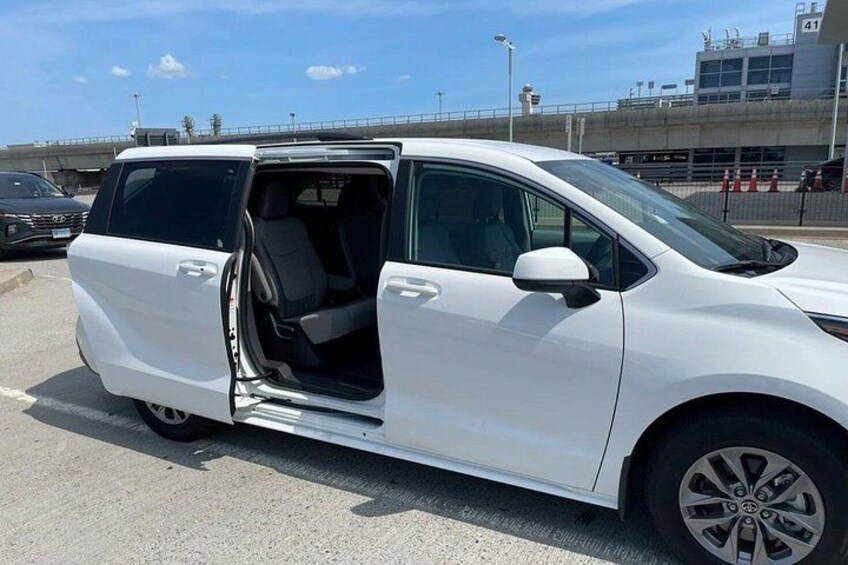 A white minivan parked in a lot with its door open, revealing the interior. 5