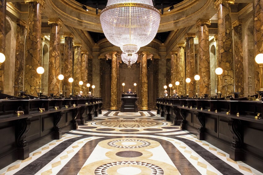 A grand hall with a large chandelier, marble columns, and ornate lighting fixtures. 4