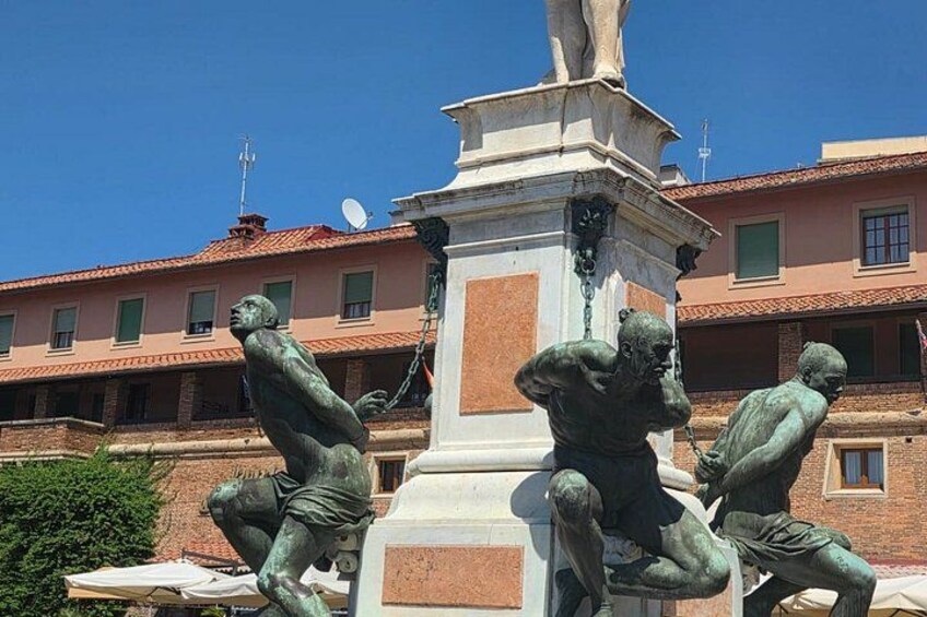 A bronze statue of a man in a dynamic pose, a pedestal, and a building with a tiled roof in the background. 4