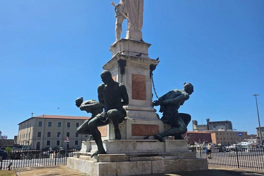 A statue with multiple figures, a clear blue sky, and a building in the background. 2