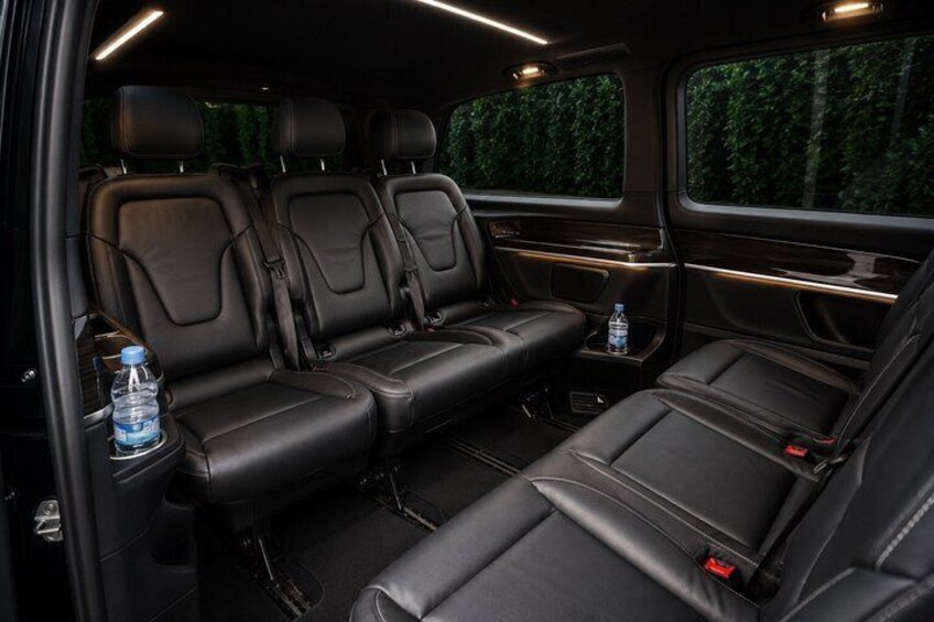 A vehicle interior with black leather seats, a central console, and a water bottle on the left side. 3