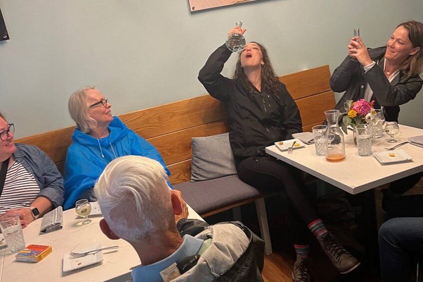 Un grupo de personas sentadas en una mesa, conversando y tomando bebidas. 5